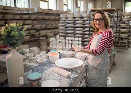 Portrait de femme potter using digital tablet in atelier de poterie