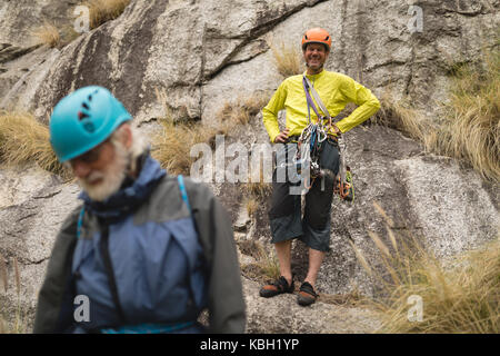 Portrait of happy man standing on rock avec son ami en premier plan Banque D'Images