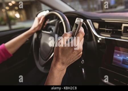 Close-up of woman using mobile phone while driving car Banque D'Images