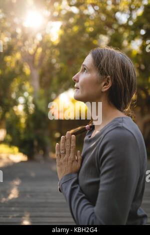 Senior woman practicing yoga dans le parc en été Banque D'Images