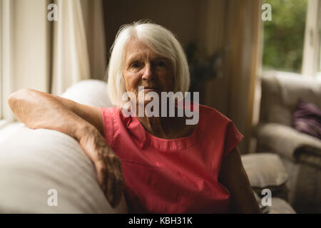Senior woman sitting on sofa in living room à la maison Banque D'Images