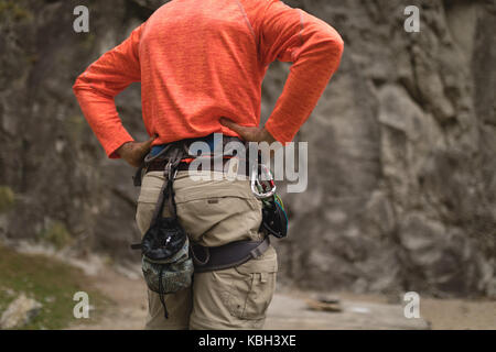 Mid section homme portant l'équipement de sécurité au cours de l'alpinisme Banque D'Images