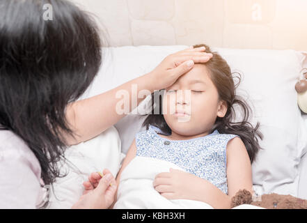 Mesure de la température de la mère de son enfant à la main. enfant malade avec une forte fièvre au lit de pose et mère tenant le thermomètre, le concept de soins de santé Banque D'Images