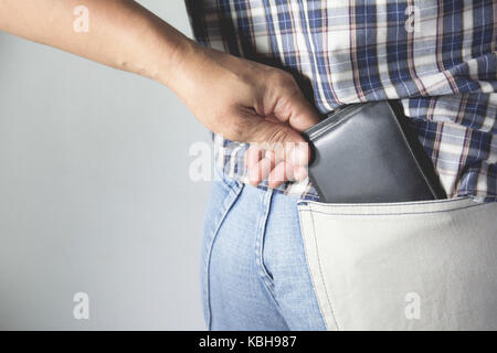 Close-up of a la main de voleur de voler le porte-monnaie pour une femme. voleur voler wallet de poche arrière, d'une femme. Banque D'Images