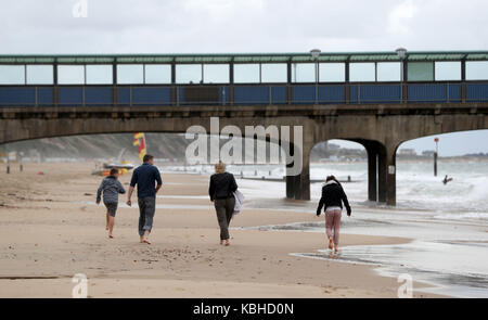 Les gens marchent le long de la plage de Boscombe Bournemouth, Grande-Bretagne, comme on est en bonne voie pour fortes pluies et tempêtes comme vestiges de l'ouragan lee ajouter "oomph" à un système de basse pression se déplaçant à travers l'Atlantique, les prévisionnistes dit. Banque D'Images