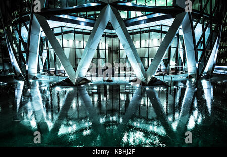 Le reflet de la base de la tour gherkin par une froide nuit pluvieuse dans la ville de Londres Banque D'Images