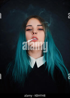 Emo girl cigarette. jeune étudiant ou l'élève avec les cheveux teints de couleur bleu, hat, lentilles,piercing,oreilles de tunnels et de coiffure inhabituelle se dresse sur bla Banque D'Images