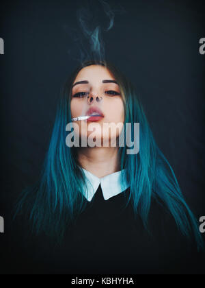 Emo girl cigarette. jeune étudiant ou l'élève avec les cheveux teints de couleur bleu, hat, lentilles,piercing,oreilles de tunnels et de coiffure inhabituelle se dresse sur bla Banque D'Images