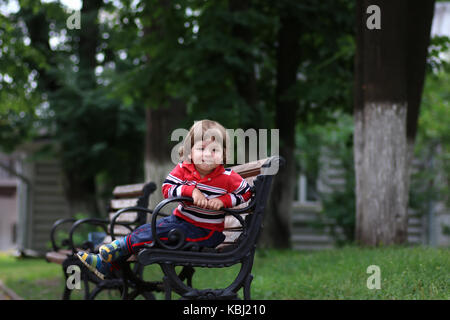 Banc enfant garçon seul parl Banque D'Images