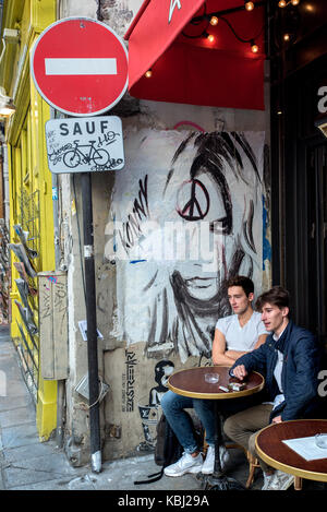 Graffiti sur un mur par un café sur la rue de Buci dans le Quartier Latin de Paris. Banque D'Images