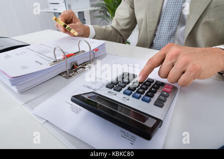 Au milieu d'hommes à l'aide comptable en maintenant calculatrice loupe sur projets in office Banque D'Images