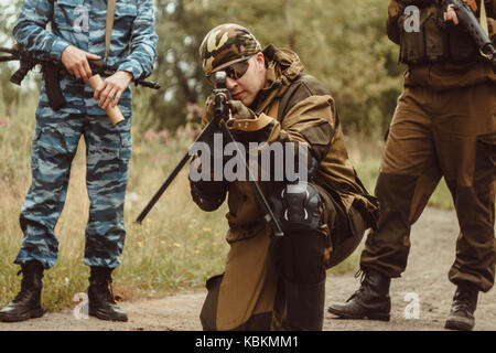 Un joueur en airsoft assis sur son genou et de visée Banque D'Images