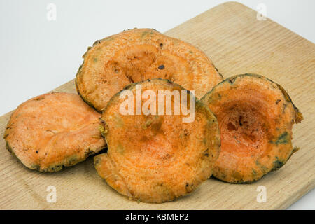 Quatre champignons du pin rouge frais, lait de safran (lactarius deliciosus) sur le conseil de cuisine sur fond blanc,fermer , vue horizontale. Banque D'Images