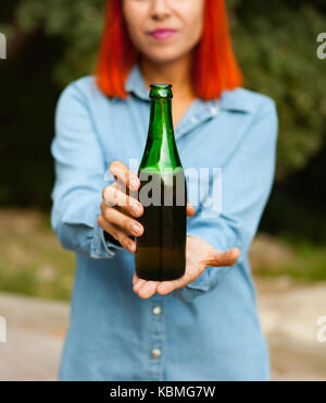 Femme rousse à la campagne le grillage avec une bouteille verte dans la campagne Banque D'Images