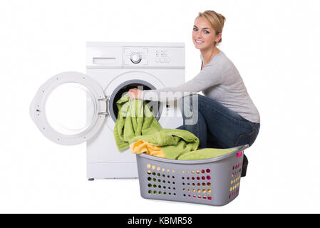 Jeune femme loading lave-linge sur fond blanc Banque D'Images