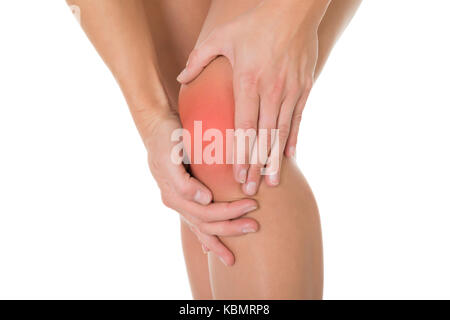 Portrait de femme souffrant de douleur au genou sur fond blanc Banque D'Images