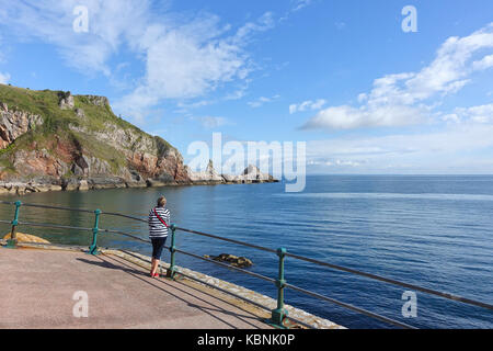 Lady Walker sur le sentier de la côte sud-ouest à Anstey's Cove, Torquay, Devon s'arrête pour admirer la formation rocheuse inhabituelle sur la tournière. Banque D'Images