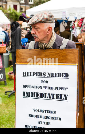 En Angleterre, Chatham Dockyard. Un homme âgé, tabagisme, portant pancarte demandant des volontaires pour aller immédiatement à l'office de recrutement. Re-enactment. Banque D'Images