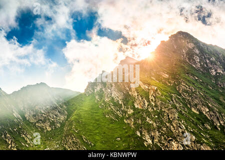 Flare soleil éclatant derrière un pic de montagne le long col transfagarasan, en Roumanie Banque D'Images