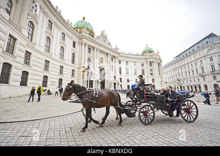 Célèbre appelé calèche fiaker passe par le Palais de la Hofburg à Vienne à Michaelerplatz avec les touristes et les gens. Banque D'Images