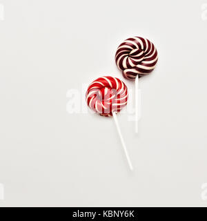 Lollipop télévision lay concept minimal deux sucettes de couleur sur fond blanc ronde classique rouge-blanc et brun-blanc candy on a stick trendy Banque D'Images