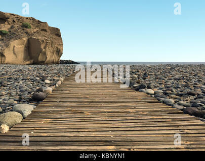 Passerelle en bois à pebble stone beach avec arrière-plan de l'océan et ciel bleu Banque D'Images