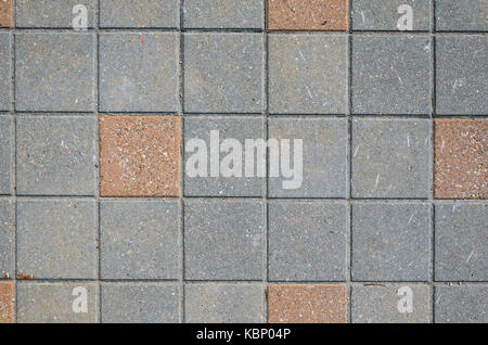 Pavés carrés de béton gris avec inserts de texture à partir d'un bloc de pierre rouge. L'aménagement paysager concept d'arrière-plan Banque D'Images