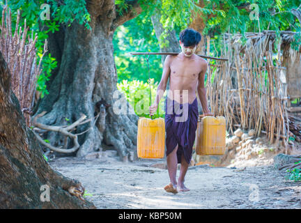 Fermier birman transportant des seaux remplis d'eau dans un village près de Bagan Banque D'Images