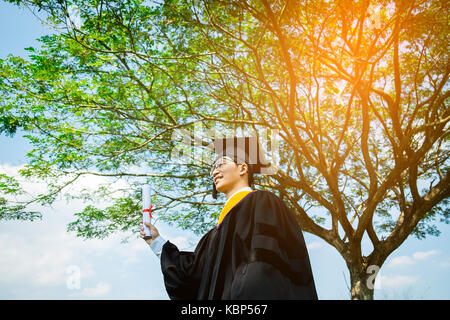 L'obtention du diplôme : student standing up et sourire holding certificat d'études avec diplôme avec expérience dans la nature. Banque D'Images