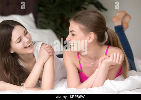 Deux jeunes copines sourire lying on bed ou bavarder. Banque D'Images