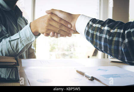 Close-up of two business people shaking hands assis à la place de travail. Banque D'Images