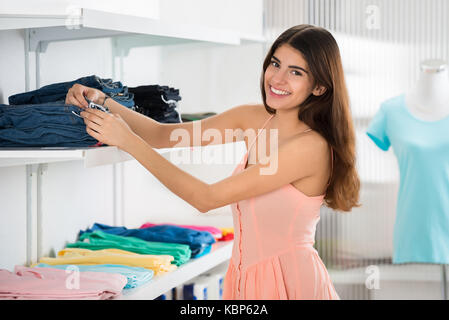 Portrait of smiling young woman choosing jeans en magasin Banque D'Images