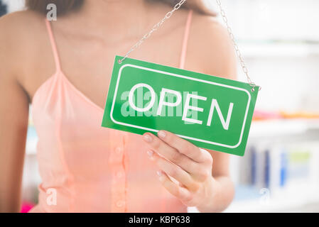 Portrait de femme propriétaire holding open sign in clothing store Banque D'Images