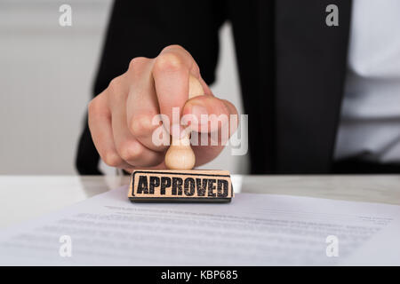 Portrait of businesswoman stamping approuvé le document contrat at desk in office Banque D'Images