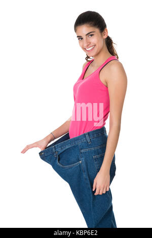 Portrait of smiling young woman showing son vieux jeans après le succès de l'alimentation sur fond blanc Banque D'Images