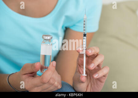 Portrait of young woman holding flacon de médicaments et de seringues à la maison Banque D'Images