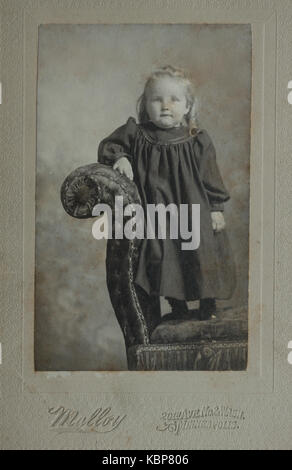 American archive monochrome studio portrait photographie de jeune enfant debout sur une chaise longue canapé, prise à la fin du XIXe siècle aux photographes Malloy, Minneapolis, Minnesota, États-Unis Banque D'Images