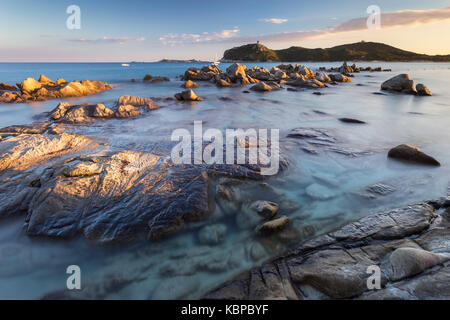 Coucher de soleil sur le récif de Porto Giunco plage et la vieille tour, Villasimius, Cagliari, Sardaigne, Italie, Europe.