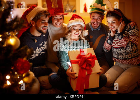 Surpris smiling woman et amis avec cadeau de Noël dans l'ouverture de fort Banque D'Images