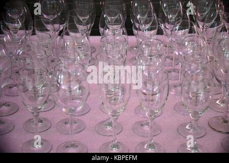 Verres à vin élégant avec lumière relections sur-le sur table avec nappe rose, verres vides dans une rangée Banque D'Images