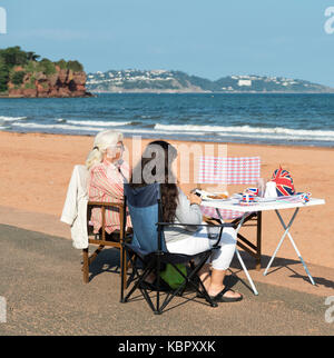 Une mère et sa fille se détendre à la plage de sable à l'extérieur de leur cabane de plage de goodrington sands paignton, bénéficiant d'une marque très britannique tasse de thé. Banque D'Images