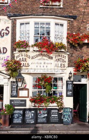 L'Angleterre, les traiter. 17e siècle King's Head Pub et inn. Face du bâtiment éclairé par la lumière directe du soleil avec ciel bleu clair au-dessus. Différents signes à l'extérieur. Banque D'Images