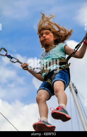 Jeune fille sautant sur trampoline bungee dans un parc d'amusement ; les cheveux des filles si battant, USA Banque D'Images