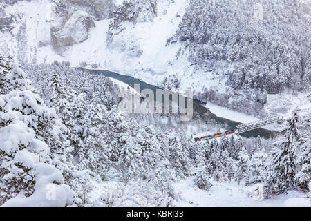 Le train passe au rouge dans la gorge malgré de fortes chutes de neige. rhein(gorge ruinaulta), Flims, imboden, Grisons, Suisse, Europe Banque D'Images