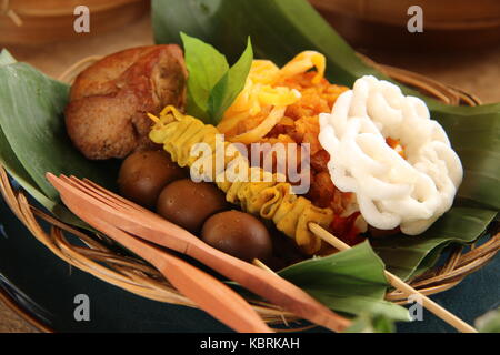 Nasi kucing tempe orek javanais. petite partie plat avec riz sauté épicé le tempeh topping et accompagnements de satays, beancurd et craquelins. Banque D'Images