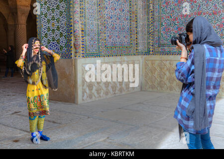 La province du Fars, Shiraz, Iran - 19 avril, 2017 : la petite fille modèle photographe photographiant la dans le costume national iranien, tandis que près de l'entrée t Banque D'Images