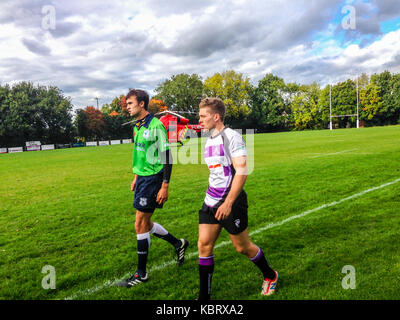 Woodford Green, Londres, Royaume-Uni. Le 30 septembre 2017. L'arbitre et le capitaine de l'équipe, confèrent que Londres's G-d'ambulance aérienne par hélicoptère 75 terrains à Woodford Rugby Football Club Highams terrain en Woodford Green en réponse à un rapport d'un spectateur victime d'une crise cardiaque. Le Woodford v Chelmsford match était suspendu pendant 40 minutes alors que les ambulanciers ont assisté à l'accident qui a été en mesure de quitter par la route. Woodford a remporté le match. L'Air Ambulance est pris en charge par les francs-maçons de Londres. Credit : Mark Dunn/ Alamy Live News Banque D'Images