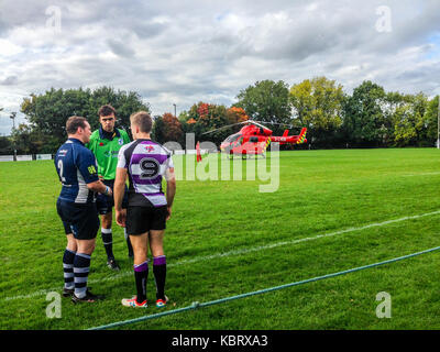 Woodford Green, Londres, Royaume-Uni. Le 30 septembre 2017. Arbitre confère avec le capitaine de l'équipe de London's G-d'ambulance aérienne par hélicoptère 75 terrains à Woodford Rugby Football Club Highams terrain en Woodford Green en réponse à un rapport d'un spectateur victime d'une crise cardiaque. Le Woodford v Chelmsford match était suspendu pendant 40 minutes alors que les ambulanciers ont assisté à l'accident qui a été en mesure de quitter par la route. Woodford a remporté le match. L'Air Ambulance est pris en charge par les francs-maçons de Londres. Credit : Mark Dunn/ Alamy Live News Banque D'Images