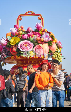 La place Tiananmen, à Beijing, Chine. 1er octobre 2017. Un jeune couple à faire des photos devant le grand panier de fleurs l'installation sur la place Tiananmen, à Beijing, Chine, sur la journée nationale de la Chine, 1er octobre 2017 : crédit liao yi/Alamy live news Banque D'Images