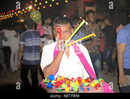 L'homme indien vente de jouets pour enfants de la rue de Delhi, Inde. Les gens qui marchent en arrière-plan. Banque D'Images